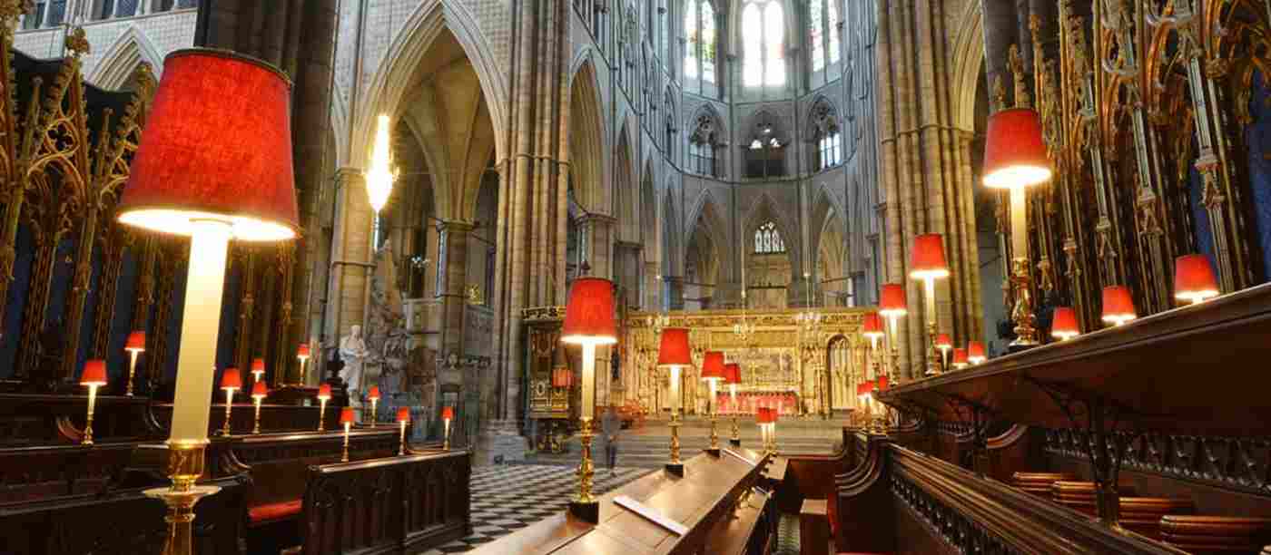 The choir stalls in Westminster Abbey, with red cushioned seats and small red lamps