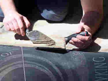 Photograph of a stone mason at Westminster Abbey working with pointing tools on a new memorial
