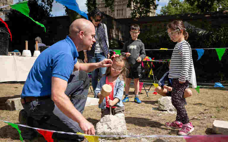 Photograph of a stone mason with children at a family event at Westminster Abbey