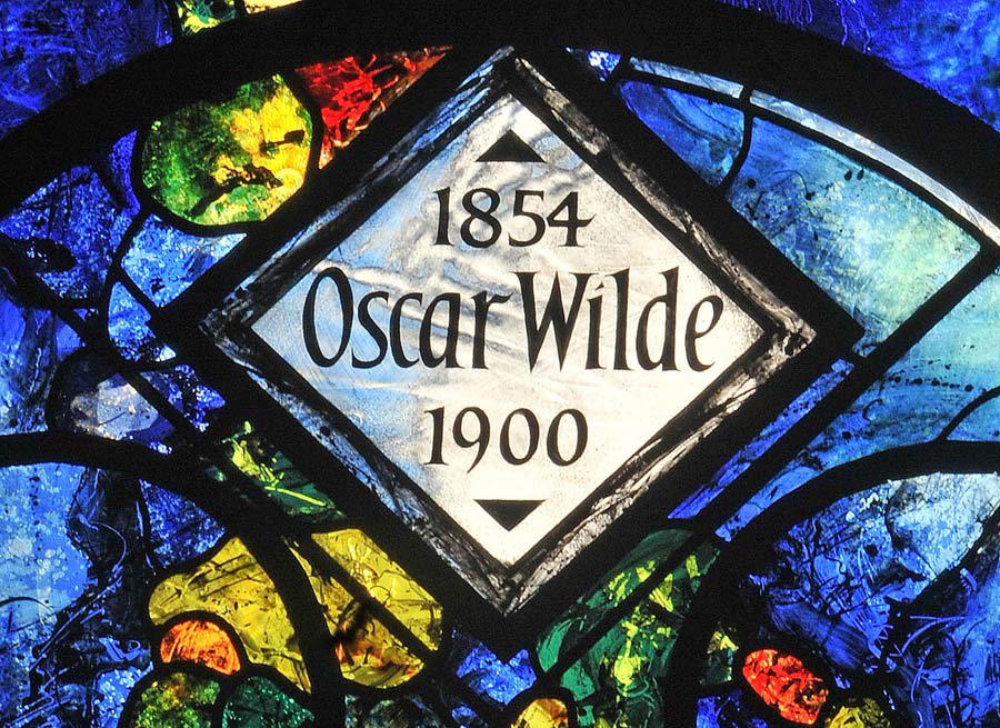 Stained glass window of white and coloured glass reading: '1854 Oscar Wilde 1900'