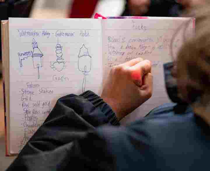 A primary school student makes notes in a notebook during a visit to Westminster Abbey