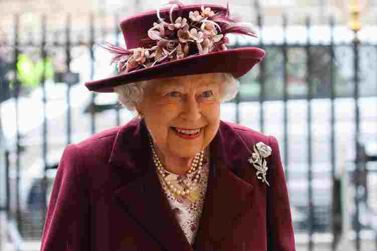 Elizabeth II wearing a maroon jacket, pink floral blouse and maroon hat decorated with pink flowers
