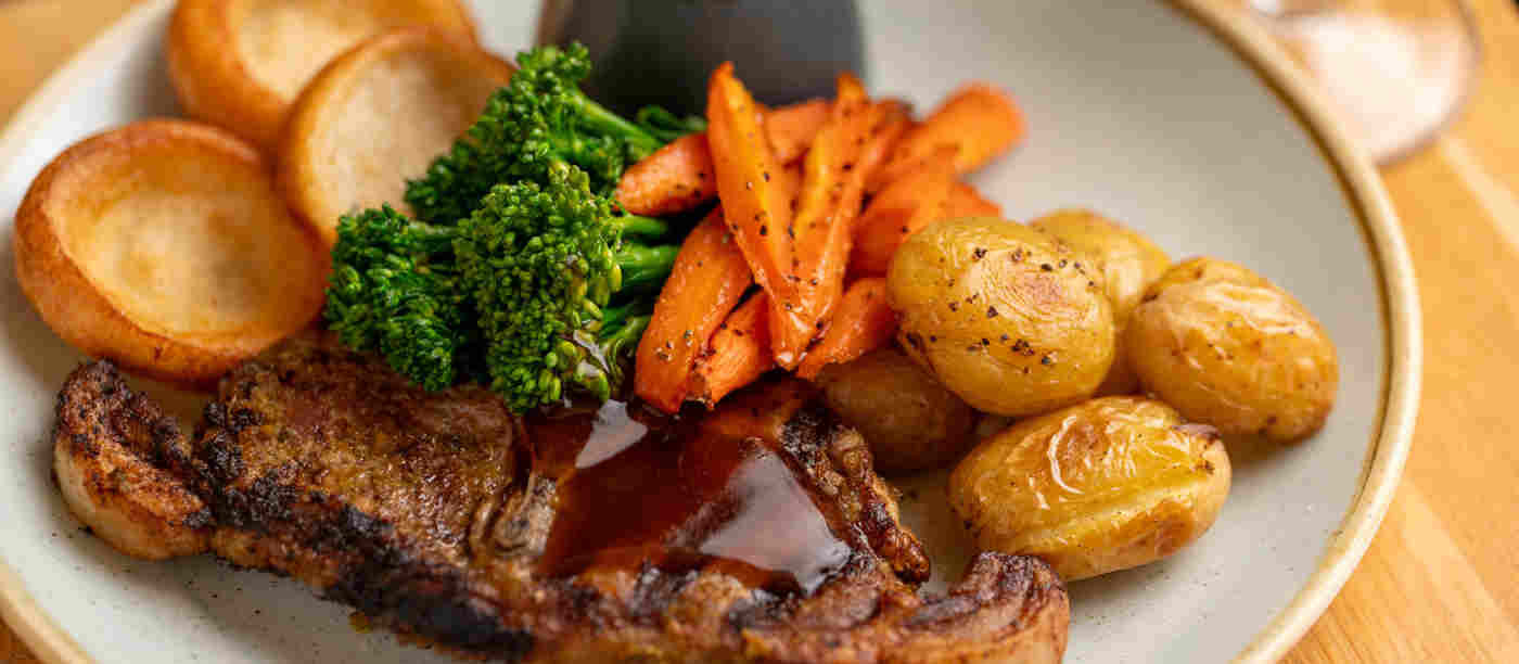 Lamb, roast potatoes, carrots and broccoli covered in gravy on a plate