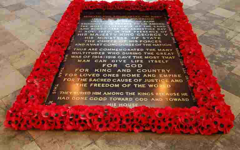 The Grave of the Unknown Warrior, a black marble gravestone with gold lettering surrounded by red poppies
