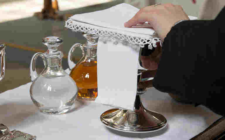Glass jugs of water and wine with a silver chalice