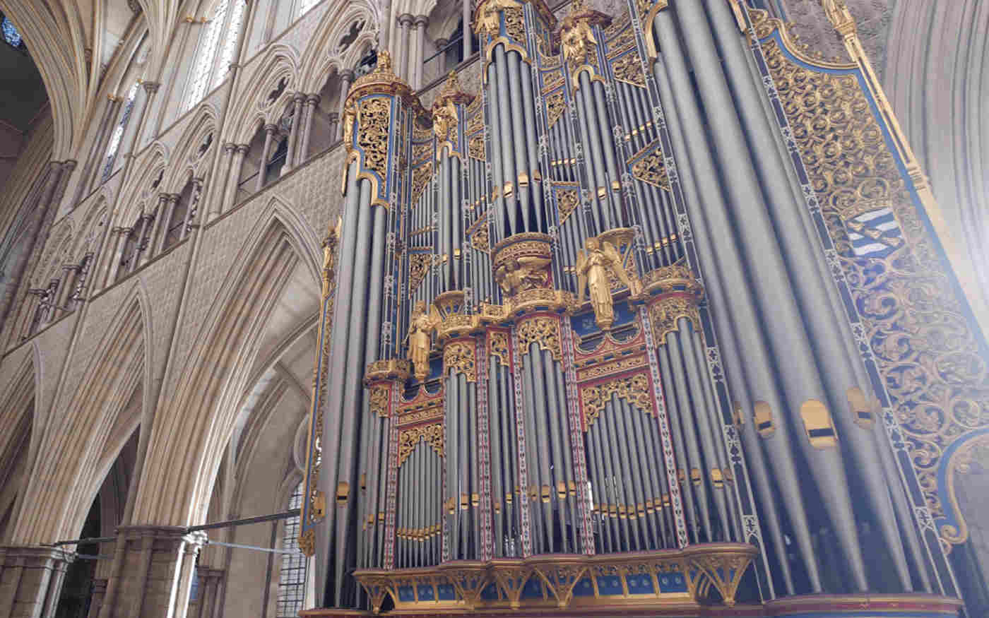 Photograph of the pipes of the organ, surrounded by the arches of the nave, within Westminster Abbey