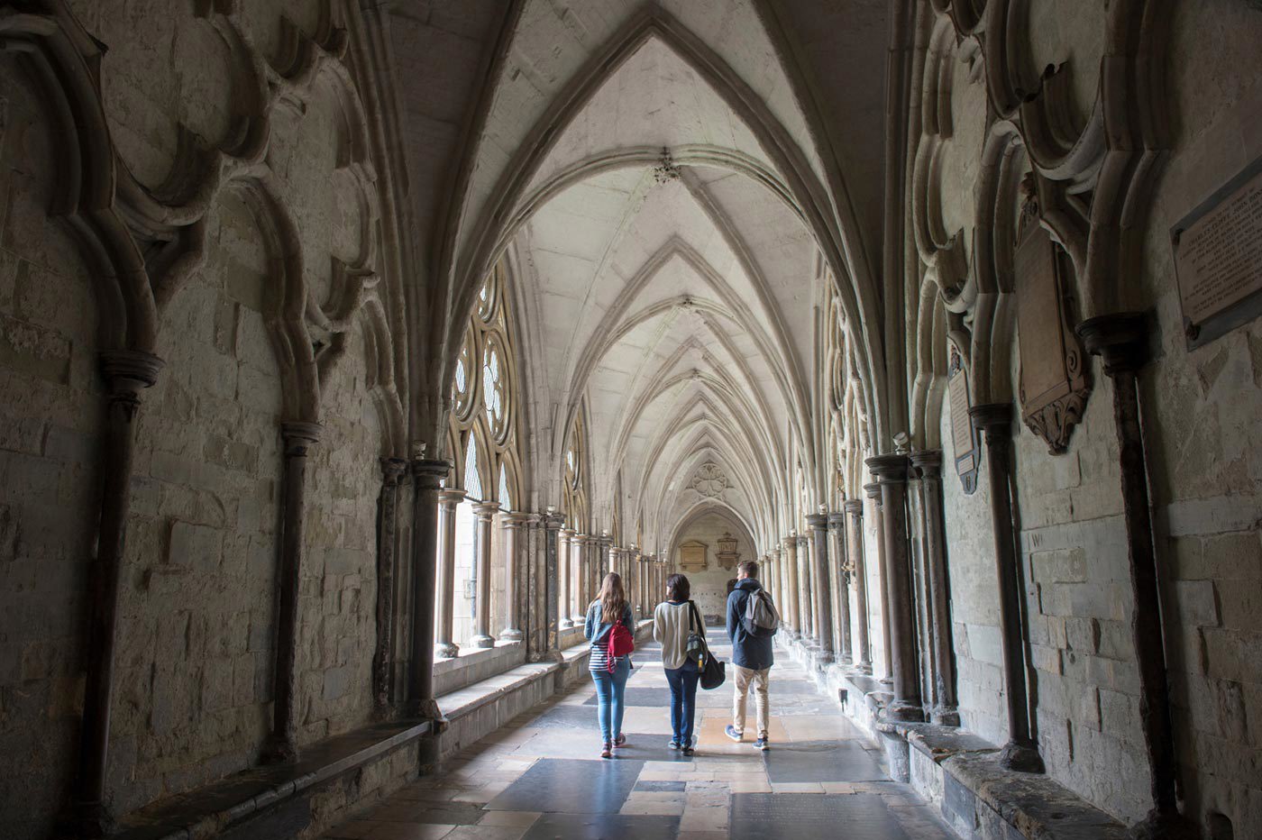 Three tourist visitors exploring the Cloisters of Westminster Abbey