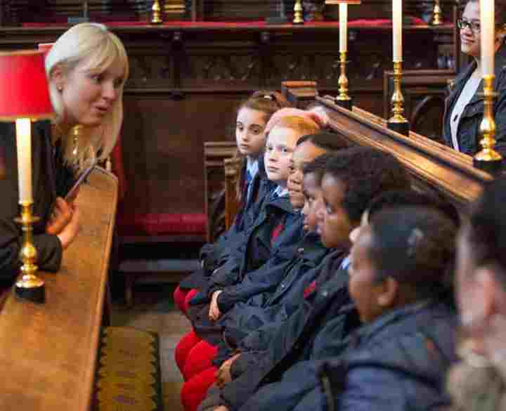 A member of the learning teams asks a primary school group a question during a tour of Westminster Abbey
