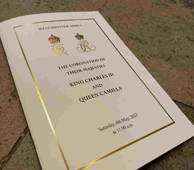 Photograph of the front cover of the Order of Service for HM King Charles III's coronation with the stone floor of Westminster Abbey in the background