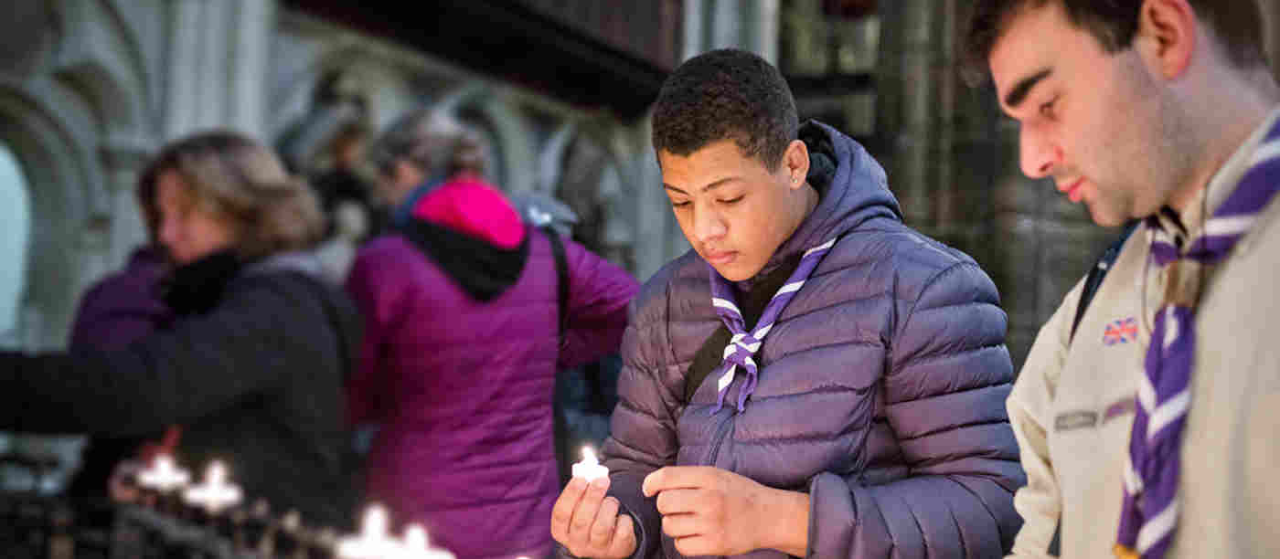 Photograph of young people lighting a candle within Westminster Abbey