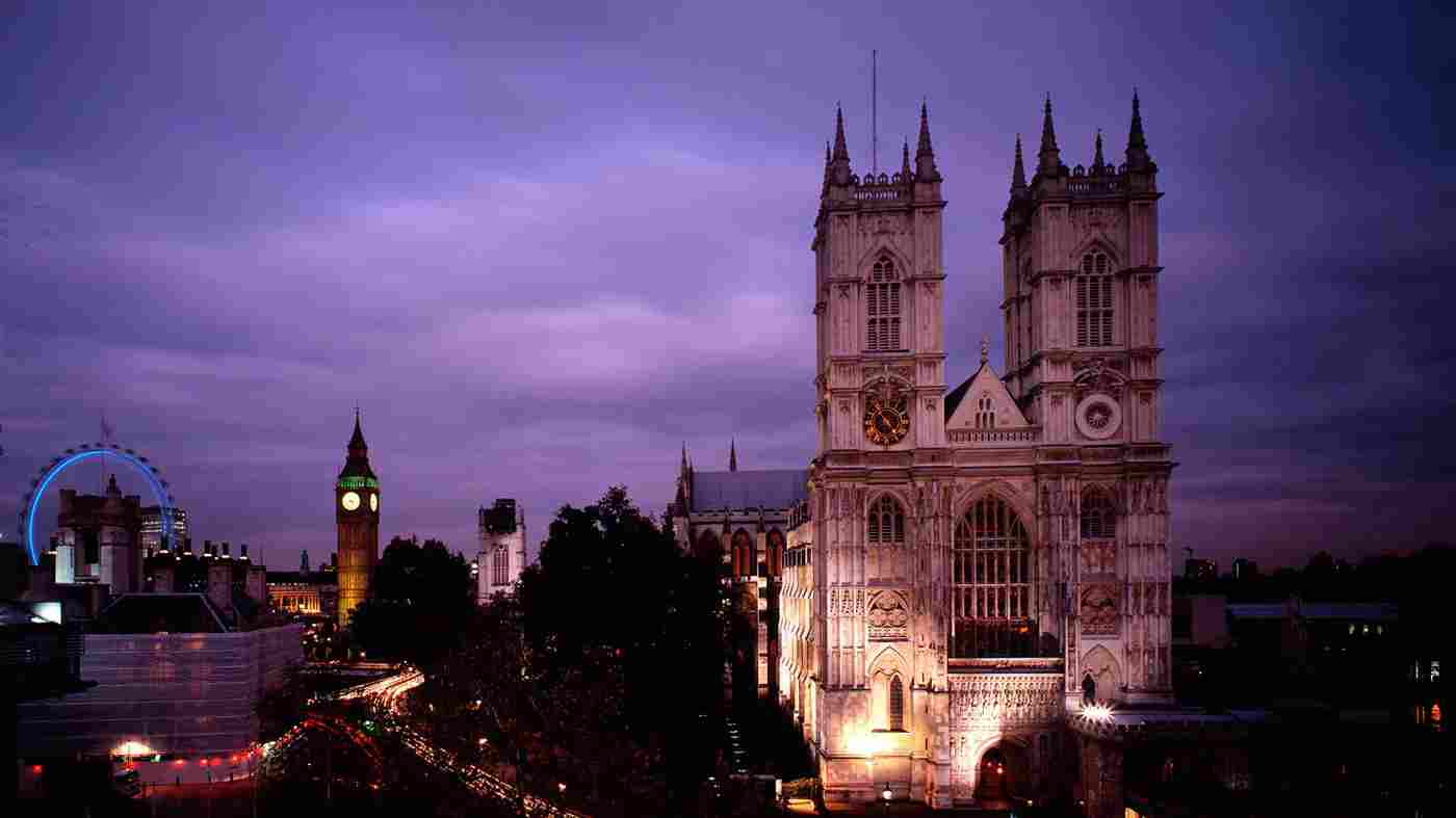Westminster Abbey at dusk with the London Eye and Big Ben behind