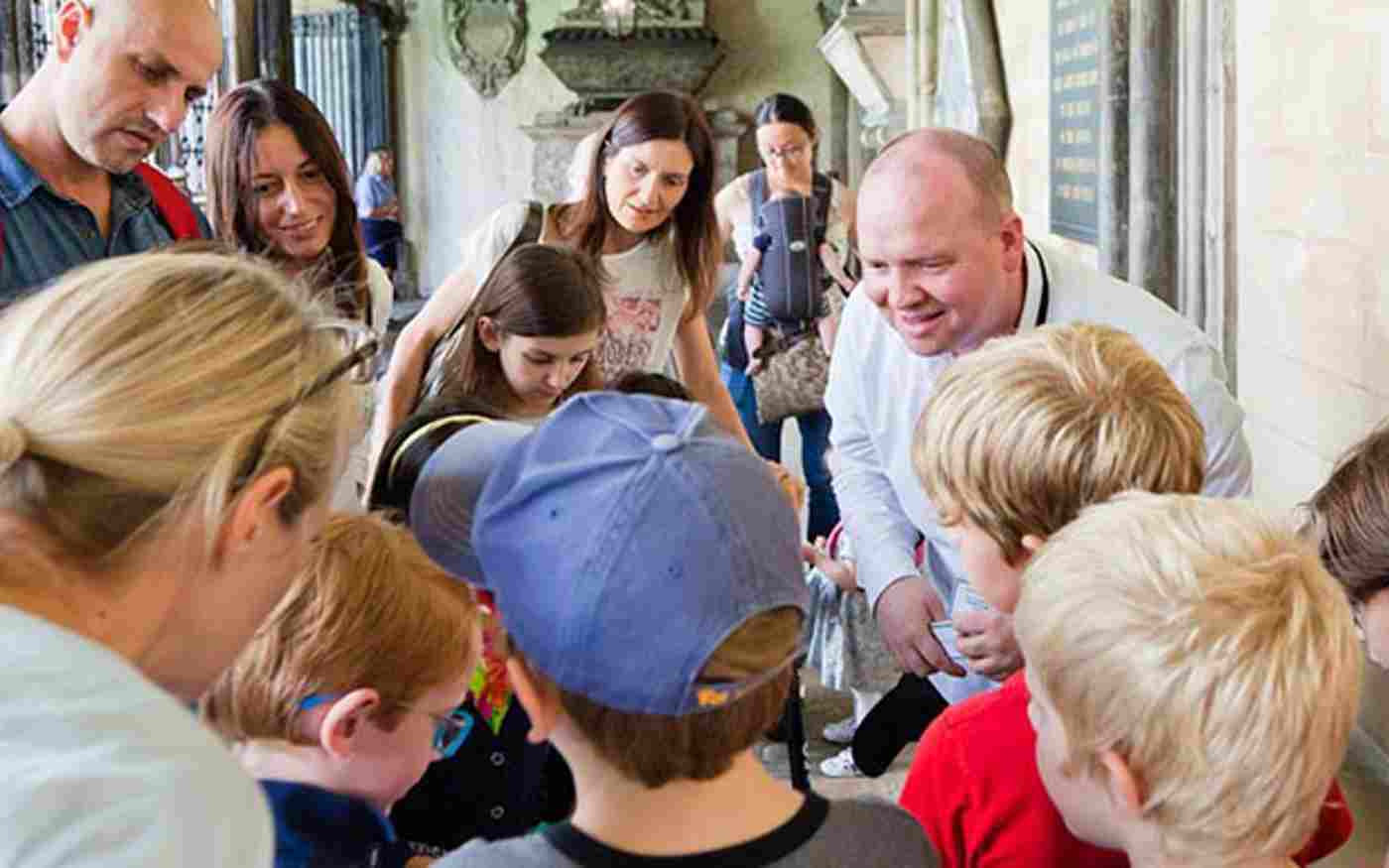 A group of children and their parents participate in a family learning session in Westminster Abbey's cloisters