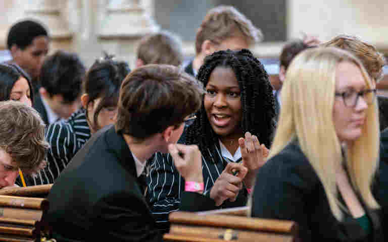 Photograph of students passionately talking to each other, seated in pews at St Margaret's Church