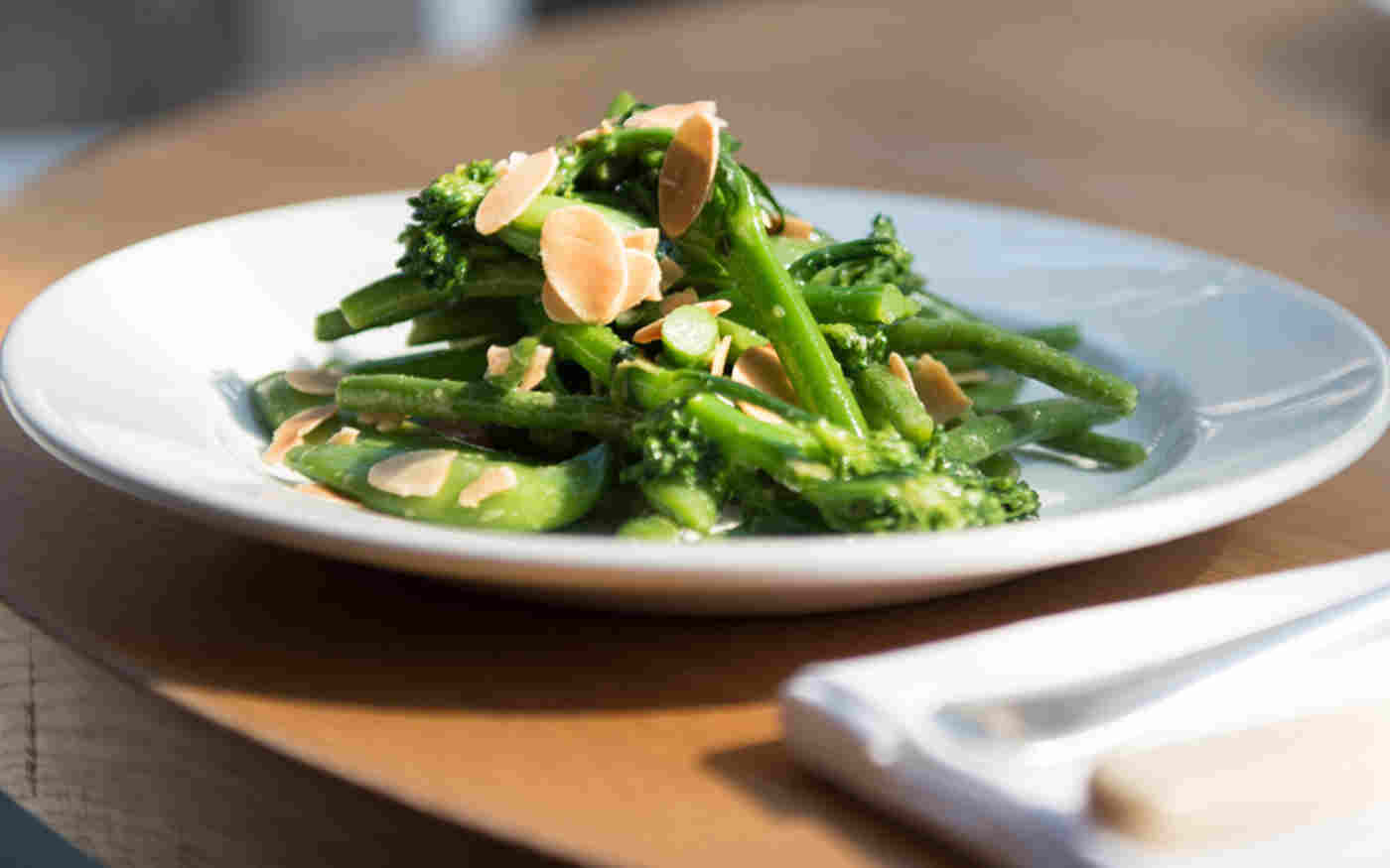 Salad of sugar snap peas and tender stem broccoli, topped with toasted flaked almonds
