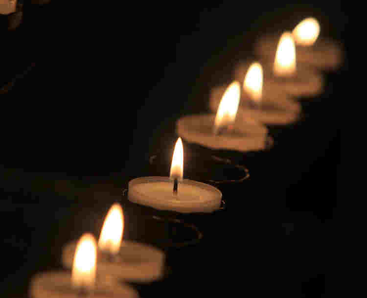 Photograph of lit candles in darkness representing memorialisation of abolitionists