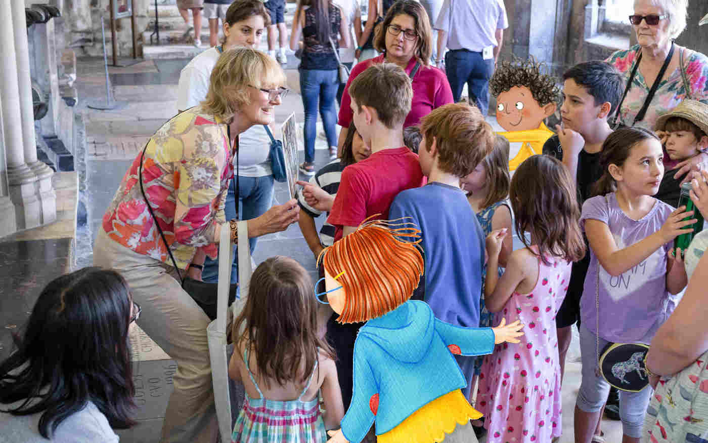 Photograph of an adult leading a tour for children and adults in the cloisters of Westminster Abbey including an illustrated child