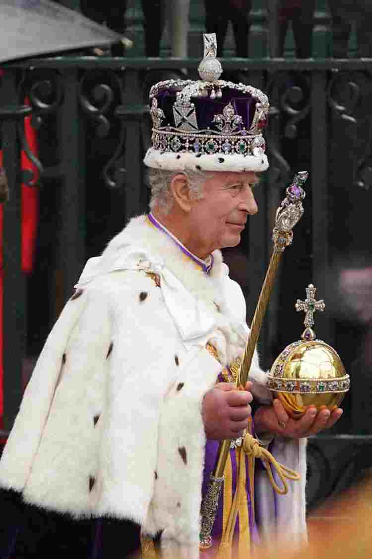 King Charles III leaves the Abbey wearing St Edward's Crown and holding the Orb and Sceptre.