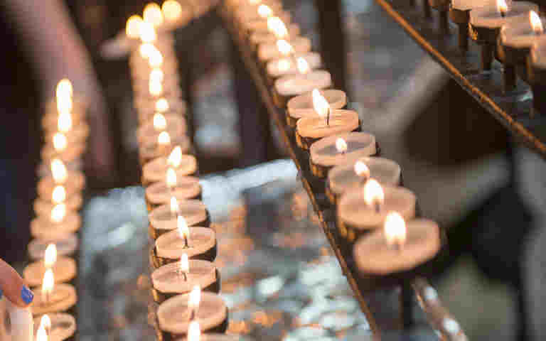 Photograph of candles being lit within Westminster Abbey, representing candles at Christmas