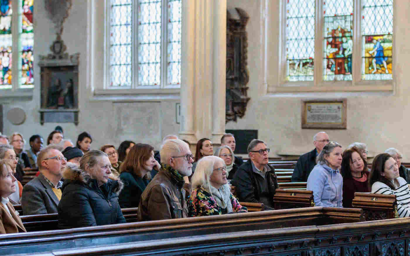 Photograph showing an audience of adults sitting in the pews of St Margaret's Church, Westminster Abbey listening to a talk