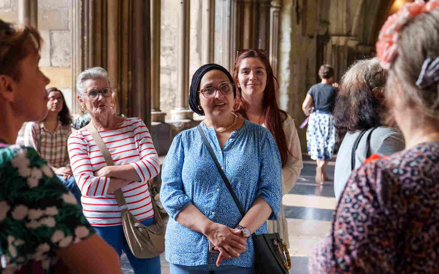 Photograph of visitors on a tour being led by a tourguide in the cloisters of Westminster Abbey
