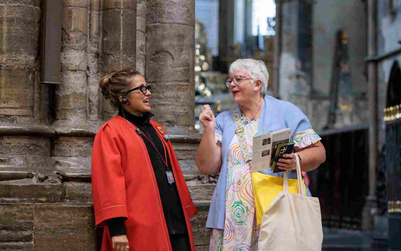 Photograph of member of the public chatting with member of staff wearing a red gown as part of visiting within Westminster Abbey