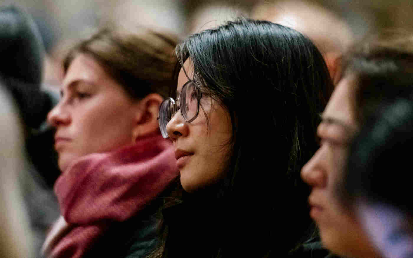 Close-up photograph of woman, with other visitors either sit, listening to a talk