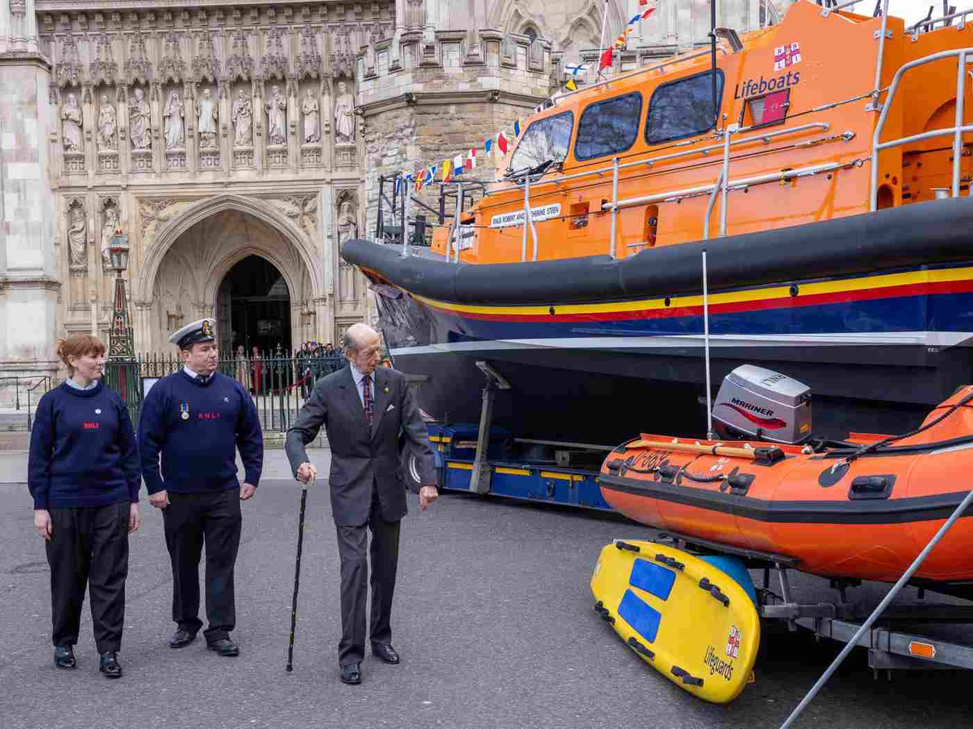 Two members of the RNLI with the Duke of Kent next to an orange lifeboat