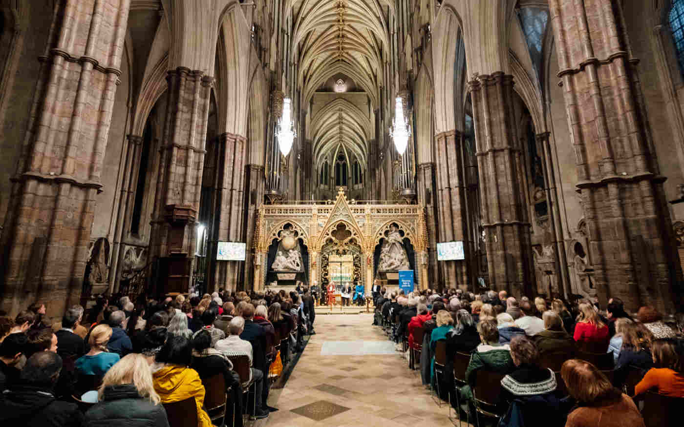 Photograph showing the backs of the audience attending a panel discussion, sitting within the Nave of Westminster Abbey